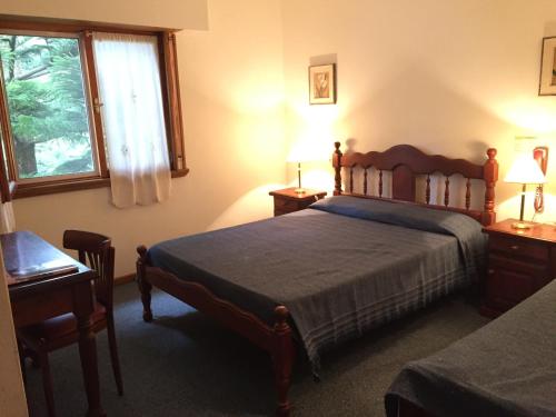 a bedroom with a bed and a desk and a window at Alpina Hostería in Villa Gesell