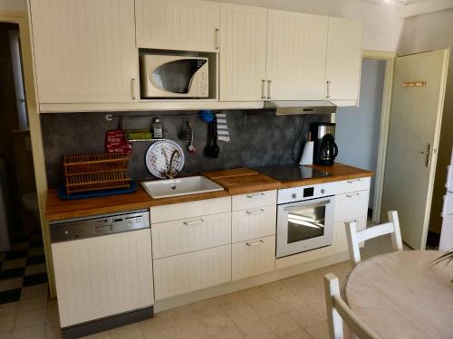 una cucina con mobili bianchi e un lavello di Le Calypso a Marseillan