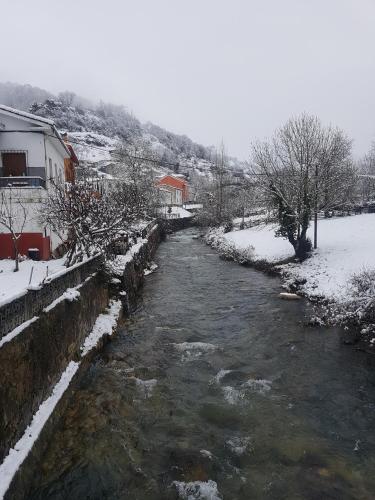 a river with snow on the ground next to a house at Hotel Peña Pandos in Felechosa