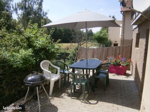 a table and chairs with an umbrella and a grill at Gîte "Le Rucher" in Romanswiller