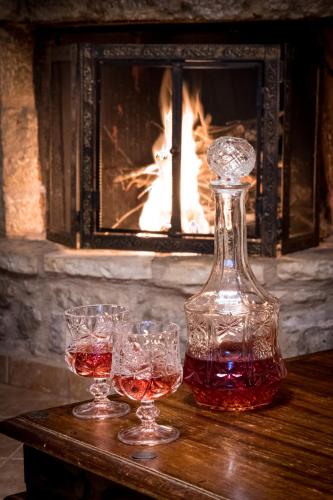three glasses of wine on a table in front of a fireplace at Lykovrisi Guest House in Arachova
