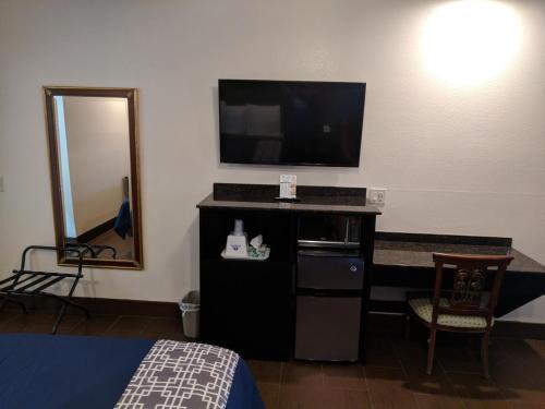 a room with a tv and a bed and a mirror at Americas Best Value Inn - Brownsville in Brownsville