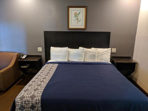 a bed in a hotel room with a blue bedspread at Americas Best Value Inn - Brownsville in Brownsville
