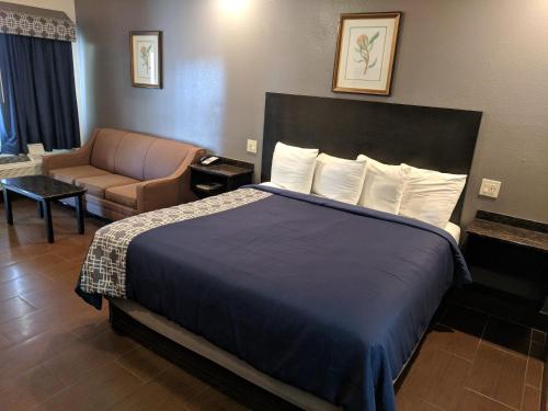 a hotel room with a bed and a couch at Americas Best Value Inn - Brownsville in Brownsville