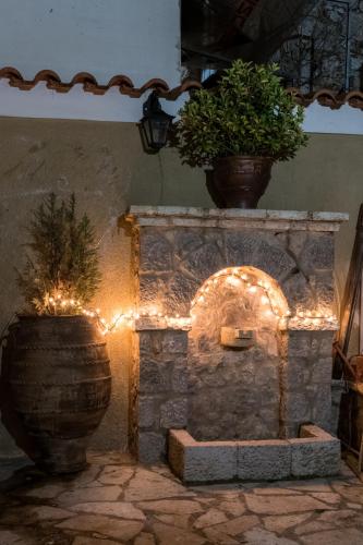 a stone fireplace with lights and a potted plant at Lykovrisi Guest House in Arachova