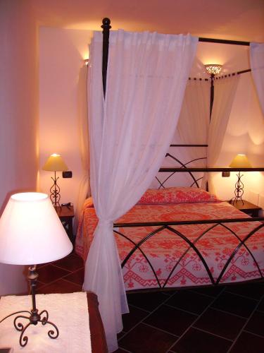 a bedroom with a canopy bed with a white curtain at Locanda Tipica Sa Corte in Oliena