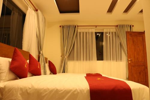a bedroom with a bed with red pillows and a window at Hoang Phuc Hotel in Thu Dau Mot