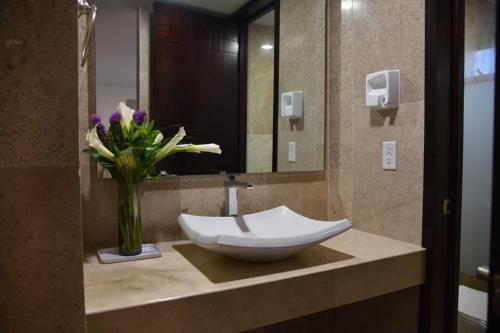 a bathroom with a sink and a vase of flowers at Suites San Pedro in Zacatecas