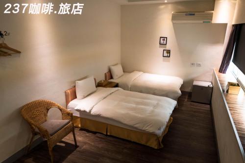 a hotel room with two beds and a chair at 237 Hotel in Kaohsiung