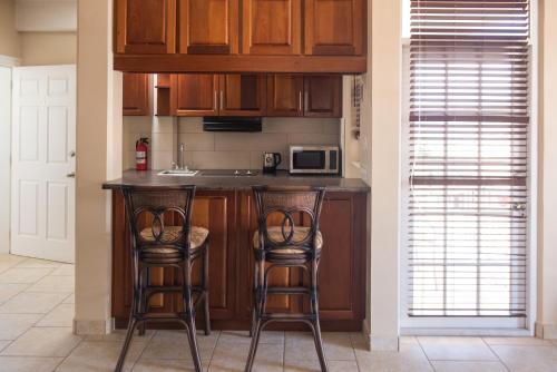 a kitchen with wooden cabinets and two bar stools at Timbo's Apartelle in Roseau