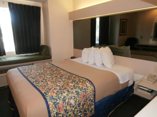 Cette chambre comprend un grand lit avec des oreillers blancs. dans l'établissement America's Best Value Inn & Suites-McDonough, à McDonough