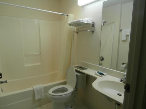 Baño blanco con aseo y lavamanos en America's Best Value Inn & Suites-McDonough, en McDonough