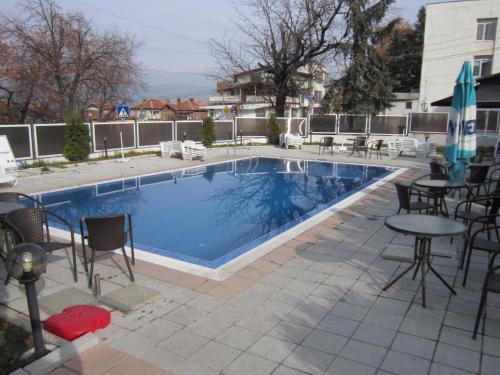 einen Pool mit Stühlen und einem Tisch daneben in der Unterkunft Germanea Hotel in Saparewa Banja