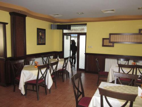 a woman standing in a dining room with tables and chairs at Germanea Hotel in Sapareva Banya