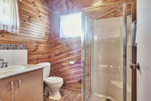a bathroom with wooden walls and a toilet and a shower at Anglesea Family Caravan Park in Anglesea