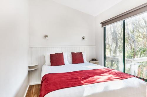 a bedroom with a bed with red pillows and a window at Anglesea Family Caravan Park in Anglesea