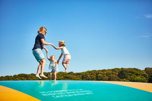 Un uomo e due bambini che saltano su un trampolino di Anglesea Family Caravan Park a Anglesea