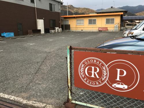 a sign on a fence in front of a parking lot at Global Resort ONO de LUNE in Hatsukaichi