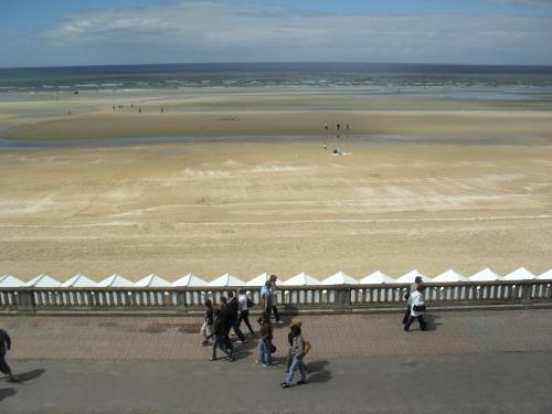a group of people walking on the beach near a beach at Cabourg Face A La Mer in Cabourg