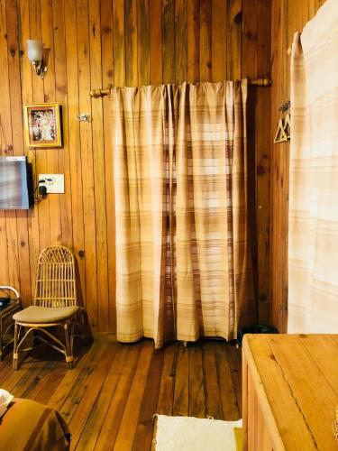 a room with a curtain and a chair and wooden floors at Aqua De Vida in Bhowāli