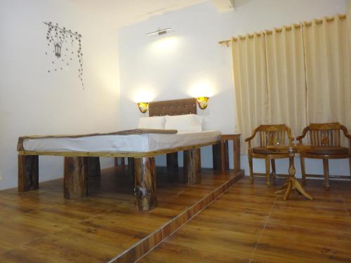 a bed in a room with a table and two chairs at Aqua De Vida in Bhowāli