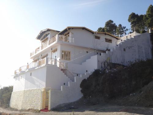 a white house on top of a stone wall at Aqua De Vida in Bhowāli