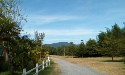 a dirt road with a fence and mountains in the background at The Creek Villa in Loei