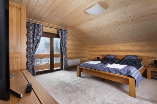 a bedroom in a log cabin with a bed and a window at Chalet - Lomnica in Tatranská Lomnica