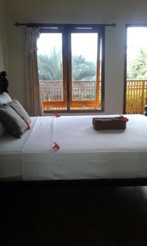 a large white bed in a room with two windows at Chika House in Gili Trawangan