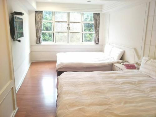 two beds in a room with a window at Maria Hotel in Zhongzheng