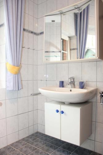 a white bathroom with a sink and a mirror at Appartementpark Seeblick in Plau am See
