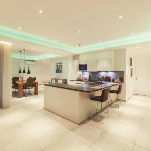 a kitchen and living room with a counter and chairs at Suncity Hotel Apartment in Accra