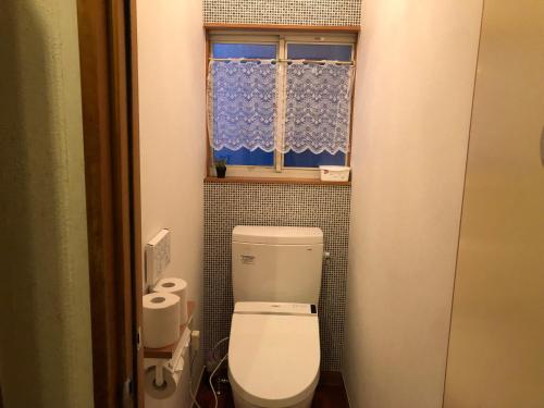 a small bathroom with a toilet and a window at Pension Razteca in Hakuba