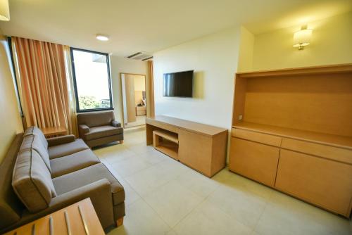 a waiting room with a couch and a tv at K Hotels Entebbe in Entebbe