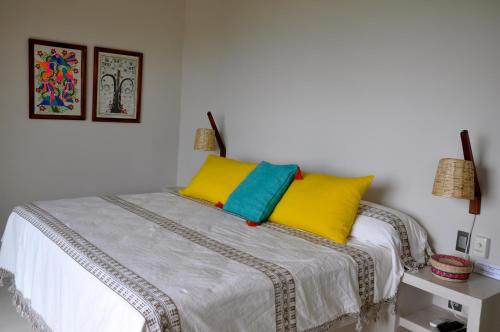 a bedroom with a bed with yellow and blue pillows at Casa Cometa in San Agustinillo