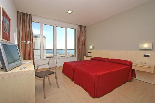 1 dormitorio con cama roja, escritorio y TV en Adiafa en Barbate