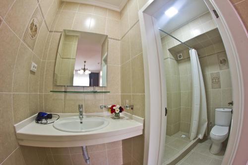 a bathroom with a sink and a toilet and a mirror at Green Yard Hotel in Karakol