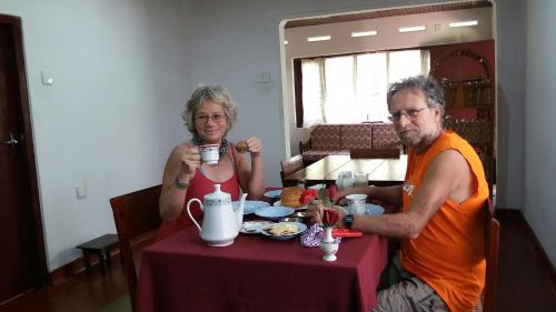 un hombre y una mujer sentados en una mesa bebiendo café en Surf reef guest house, en Mirissa