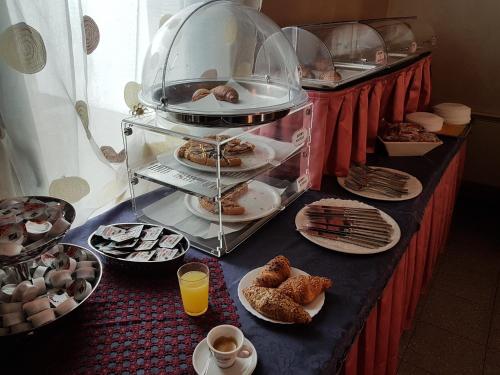 a table topped with plates of pastries and cups of coffee at Master Hotel in Castelvetro Piacentino