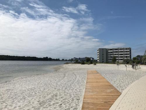 ハイリゲンハーフェンにあるStrandGut inkl Wäsche Setの水辺の木製の遊歩道があるビーチ