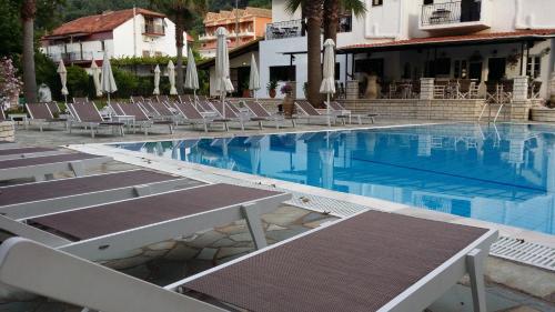 a swimming pool with lounge chairs in a hotel at Alfa Hotel in Parga