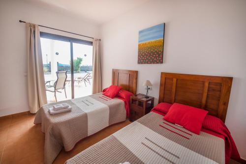 プラヤ・ブランカにあるVillas Blancasのベッドルーム1室(赤い枕のベッド2台付)