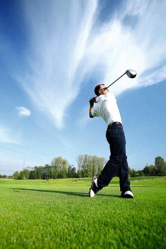 un homme qui frappe un ballon de golf avec un club dans l'établissement Roulottes de Bois le roi, à Bois-le-Roi