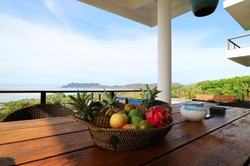 a basket of fruit on a wooden table on a balcony at Villa Nambung in Selong Belanak