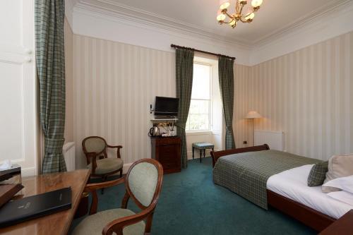 a hotel room with a bed and a table and chairs at Loch Ness Country House Hotel in Inverness