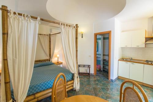 Luna di Ponente في لامبيدوسا: غرفة نوم بسرير مظلة مع طاولة وكراسي