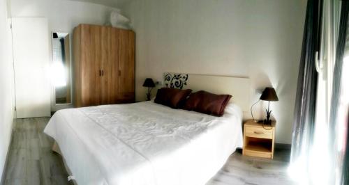 a bedroom with a white bed and a wooden cabinet at Temporary Alicante HM in Alicante