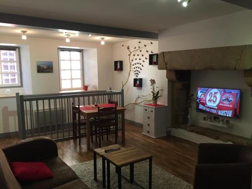 sala de estar con chimenea, mesa y TV en Appartement T3 en souplex sur le port de Saint Goustan, en Auray