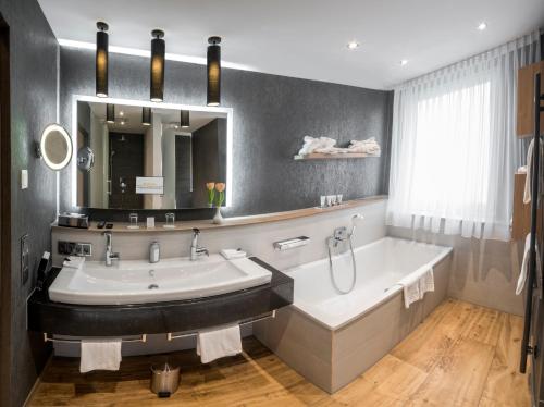uma casa de banho com uma banheira, um lavatório e um espelho. em Drei Loewen em Munique