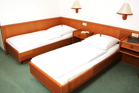 two beds in a room with two nightstands at Hotel Blocksberg in Wernigerode